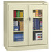 A Tennsco standard storage cabinet with a C-thru door and glass doors filled with books and files.