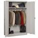 A light gray metal Tennsco jumbo wardrobe cabinet with solid doors holding clothes and shoes.