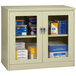 A Tennsco putty jumbo storage cabinet with C-thru doors with a few boxes on it.