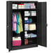 A black metal Tennsco combination cabinet with solid doors and items on the shelves.
