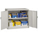 A light gray Tennsco metal storage cabinet with solid doors and many boxes inside.