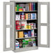 A Tennsco light gray metal storage cabinet with C-Thru doors filled with various items.