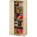 A Tennsco sand metal storage cabinet with solid doors and shelves full of items.