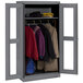 A dark gray metal Tennsco wardrobe cabinet with open C-thru doors holding coats and jackets.