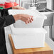 A person's hand opening a white Choice polypropylene container.