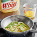 A pan of food cooking on the stove with yellow liquid in a measuring cup.