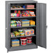 A Tennsco dark gray metal storage cabinet with shelves full of items.