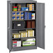 A dark gray Tennsco storage cabinet with solid doors filled with boxes.