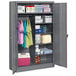 A dark gray Tennsco metal cabinet with items on the shelves.