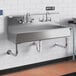 A stainless steel Regency wall-mounted utility sink with (2) faucets.