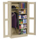 A Tennsco sand metal combination cabinet with C-Thru doors filled with items.