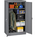 A dark gray Tennsco metal storage cabinet with solid doors filled with items.