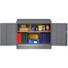 A metal Tennsco dark gray storage cabinet with books and folders.