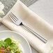 An Acopa stainless steel salad fork on a plate with a salad.