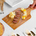 A person holding an Enjay marble and wood cake board with food on it.