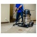 A man using a Powr-Flite wet/dry vacuum to clean the floor in a corporate cafeteria.