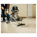 A man using a Powr-Flite wet / dry vacuum to clean the floor.