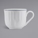 A white Tuxton china cup with a blue rim and embossed design.