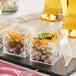 A group of Visions clear plastic mini cubes with food in them on a table.