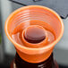 A Fineline plastic cup with an orange lid filled with orange liquid.