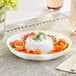 A white plastic mini circular dip tray with salmon and cream on it with green sprigs of dill.