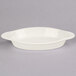 An oval white Tuxton rarebit dish with a handle.