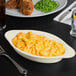 A Tuxton oval china dish with macaroni and cheese on a table.