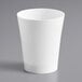 A Choice white plastic shot glass on a gray surface.