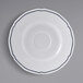 A white Tuxton saucer with a scalloped edge and blue trim.