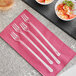 A group of Visions clear plastic forks on a pink napkin.