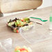 A salad in a World Centric clear plastic container with a hinged lid on a table.