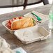 A sandwich in a World Centric compostable fiber hoagie box on a table.