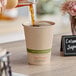 A person pouring coffee into a World Centric natural paper hot cup.