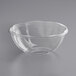 A clear plastic World Centric deli bowl on a gray surface.