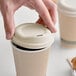 A hand using a World Centric fiber hot cup sip lid on a coffee cup.