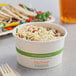 A bowl of rice and beans in a World Centric compostable paper bowl with a wooden fork on the table.