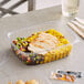 A World Centric compostable rectangular deli container filled with food on a table.