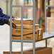 A man in a blue shirt using a Lavex U-Boat utility cart to deliver a stack of boxes.