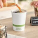 A person pouring compostable coffee into a World Centric white paper hot cup.