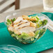 A salad in a World Centric clear plastic deli bowl on a table.