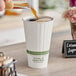 A person pouring coffee into a World Centric white compostable paper hot cup.