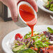 A person pouring Kraft Catalina dressing over a salad