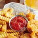 A white plate with a bowl of Heinz chili sauce and french fries.