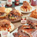 A table with food on it including a red container of Mike's Hot Honey.