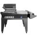 A Sealer Sales compact L-bar sealer with a hooded shrink chamber on wheels with a lid open over a table.