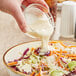 A person pouring Kraft Coleslaw Dressing into a bowl of coleslaw.