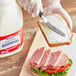 A person cutting a sandwich on a counter in a deli.