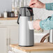 A person using a Bunn Zojirushi Lever Action Airpot to pour coffee.