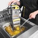 A person using a VITO fryer oil filtration machine on a counter in a professional kitchen.