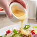 A person pouring Kraft Golden Italian dressing on a salad at a salad bar.